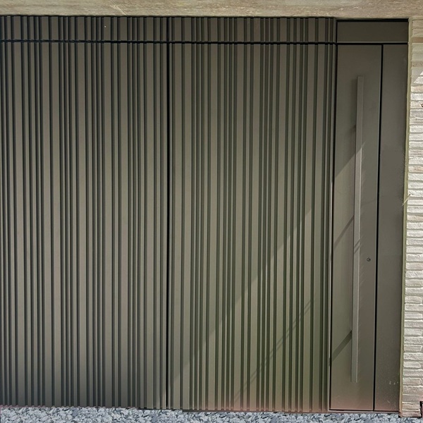 Vorgehängte hinterlüftete Fassade mit flächenbündigem Garagentor als Rohrfassade an einem Einfamilienhaus